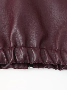 Detailed macro view of burgundy PU leather jacket elastic hem with metallic zipper