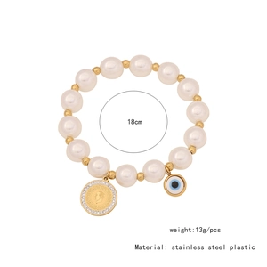Detailed view of evil eye and coin pendants on a beaded stainless steel bracelet