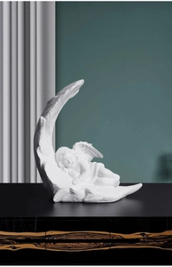Close-up of a white resin angel sleeping on a feather base for home decor