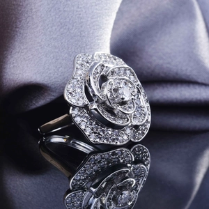 Macro shot of silver rose ring with pavé crystals and central stone on a black surface