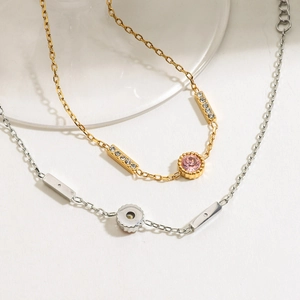 Elegant stainless steel bracelets with pink zircon and gear charms on white surface