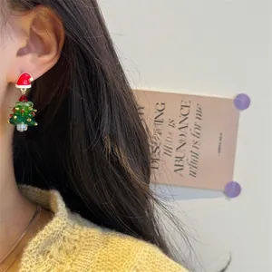 Close-up of beaded Christmas tree earrings with a red bow on a model ear