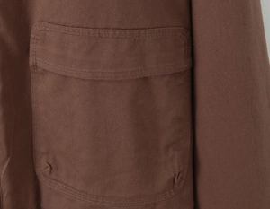 Detailed close-up showing brown twill cotton fabric texture and double-stitched pocket design
