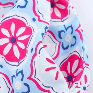 Close-up of geometric floral print fabric on a V-neck shirt dress with pink and blue details