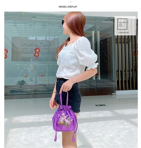 Detail of purple silk drawstring bag with floral embroidery and elegant handle