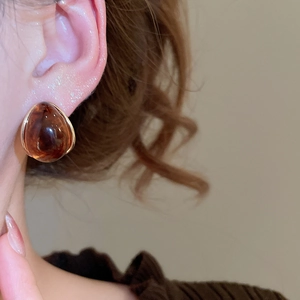 Close-up of amber resin teardrop earring worn by a model in warm light