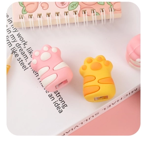 Close-up of cute cat paw silicone cable protectors in pink and yellow on an open book