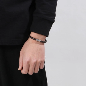 Gros plan d'un bracelet en cuir tressé marron avec boucle magnétique sur un poignet