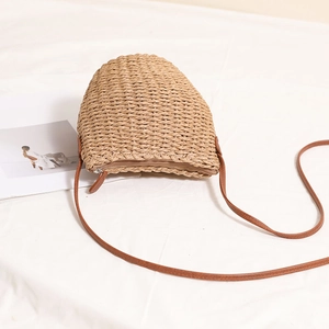 Handmade beige woven straw bucket bag with brown leather strap for summer beach vacation