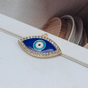 Detailed close-up of golden Evil Eye pendant with blue enamel and sparkling rhinestones