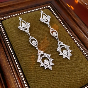 Detail of silver drop earrings with crystals on luxury green velvet background