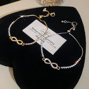 Close-up of gold and silver infinity bracelets with cubic zirconia on black velvet heart