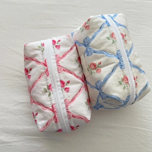 Set of two floral quilted makeup bags with ribbon bow details and zipper closure