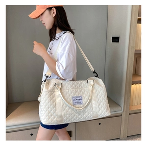 Model wearing a white quilted large travel bag with adjustable strap in modern interior