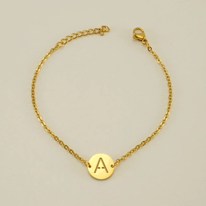 Dettaglio di un bracciale dorato in acciaio inossidabile con ciondolo lettera A e moschettone