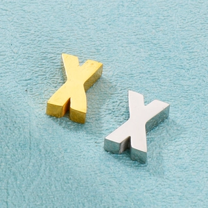 Détail de breloques en forme de X en acier inoxydable or et argent sur fond bleu