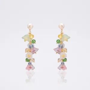Detailed macro of colorful crystal beaded earrings with pastel floral charms and pearl studs