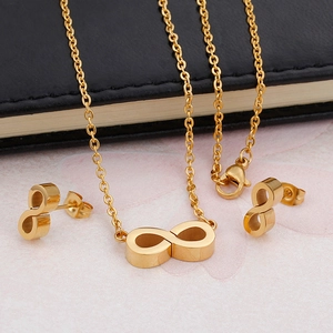 Golden infinity symbol necklace and stud earrings set on a black notebook background