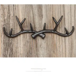 Close-up of vintage cast iron antler wall hook with rustic texture on wooden background