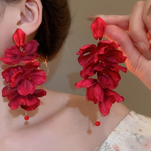 Detail view of large red silk flower earrings with pearl tassels and delicate chains
