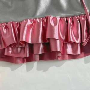 Detail of grey velvet fabric stitched with triple-layered metallic pink ruffled hem