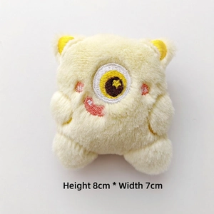 Detail shot of yellow plush monster toy showing 8cm height and 7cm width dimensions