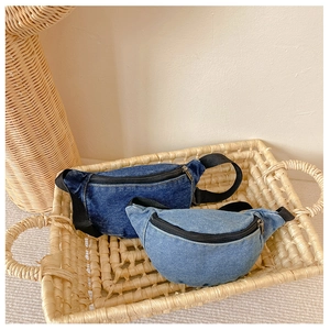 Kids denim waist bags in dark and light blue colors shown in a woven storage basket