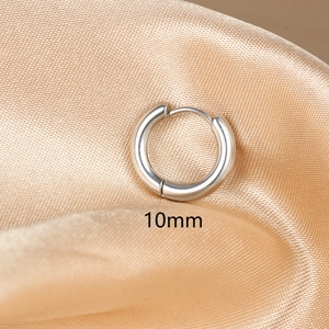 Detail shot of 10mm polished silver stainless steel huggie hoop earring on silk fabric