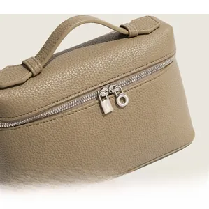 Detail of taupe pebbled leather handle and silver lock on high-end handbag