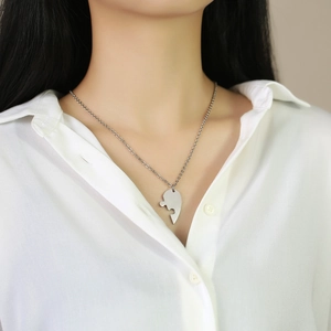 Close-up of a silver-toned broken heart puzzle pendant necklace on a female model