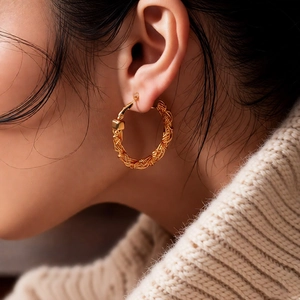 Detail of woven texture on 24k gold plated round hoop earring shown on model
