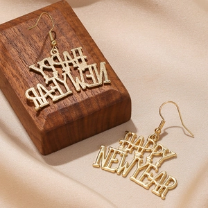 Dettaglio di orecchini dorati Happy New Year su seta e supporto in legno