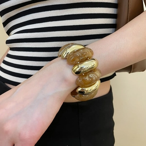 Detail of chunky gold links and amber marble resin sections on a stylish bracelet