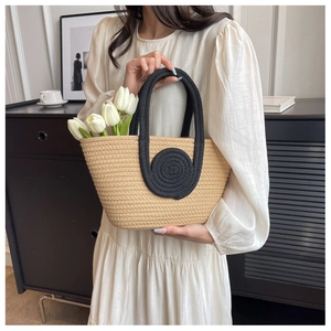 Detail of a beige woven tote bag with black rope handles and fresh white tulips inside