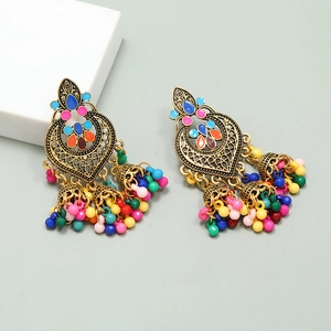 Detail of Bohemian golden tassel earrings with multi-colored beads on a grey backdrop