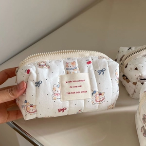 Detail of white quilted cosmetic bag with cute puppy patterns and beige woven label