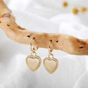 Detail of 18K gold plated heart earrings hanging on branch with smooth center and texture