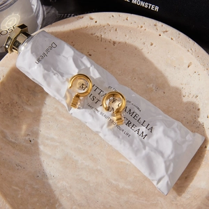 Detailed close-up of 18K gold-plated C-shaped earrings with round white zircon accents