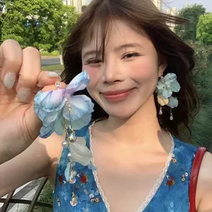 Detail of floral chiffon petal earrings with pearls, crystals, and long gold tassels