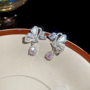 Macro view of silver butterfly earrings with pink teardrop zircon and white inlay