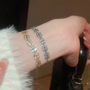 Detailed macro view of adjustable cubic zirconia clover bracelets in gold and silver finish