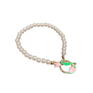 Elegant pearl bracelet with pink tulip charm and golden OT buckle on white background