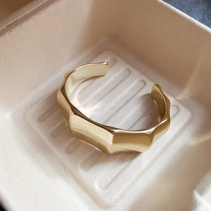 Macro shot of gold-plated wavy geometric bangle with matte finish in a gift box