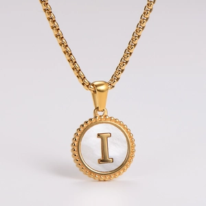 Close-up of golden shell pendant with letter I and beaded texture on stainless steel chain
