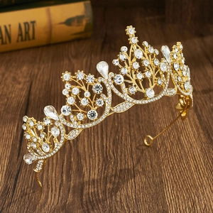 Close-up of golden baroque crown with teardrop crystals on a dark wood surface