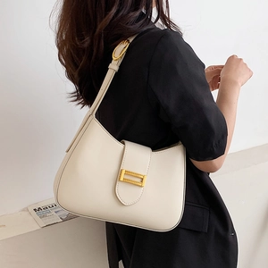 Minimalist cream white baguette shoulder bag with gold hardware shown on shoulder