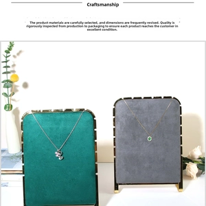 Detail view of gold and silver necklaces with floral and green gem pendants on velvet boards