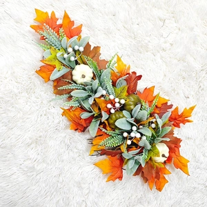 Detail of autumn harvest swag with white pumpkins and maple leaves on white faux fur