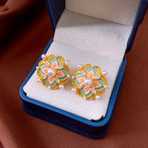 Macro detail of vintage floral earrings with mint enamel and pearls in a velvet jewelry box