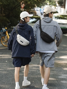 Unisex nylon crossbody chest bags in black and white shown in an outdoor street setting